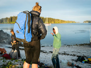 Woman on beach wears Sagebrush Dry blue dry daypack backpack