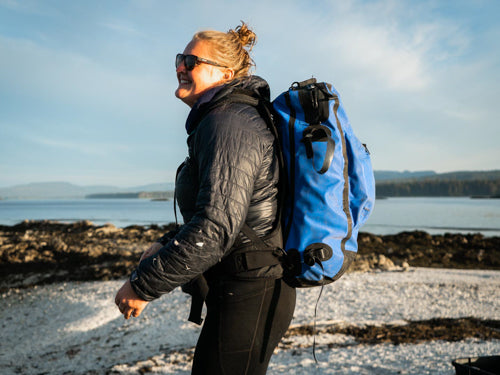 Woman on beach wears Sagebrush Dry blue dry daypack backpack