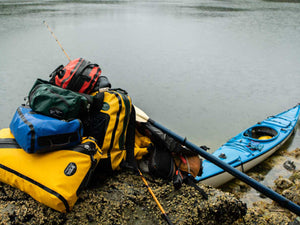 Kayak and pile of Sagebrush Dry Gear packs