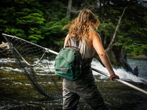Woman fishes wearing Sagebrush Dry Gear Green Hip & Deck Pack